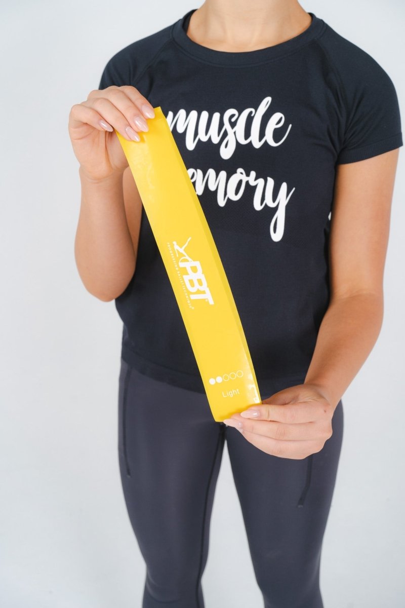 Yellow PBT mini-loop band stretched for arm and shoulder strengthening