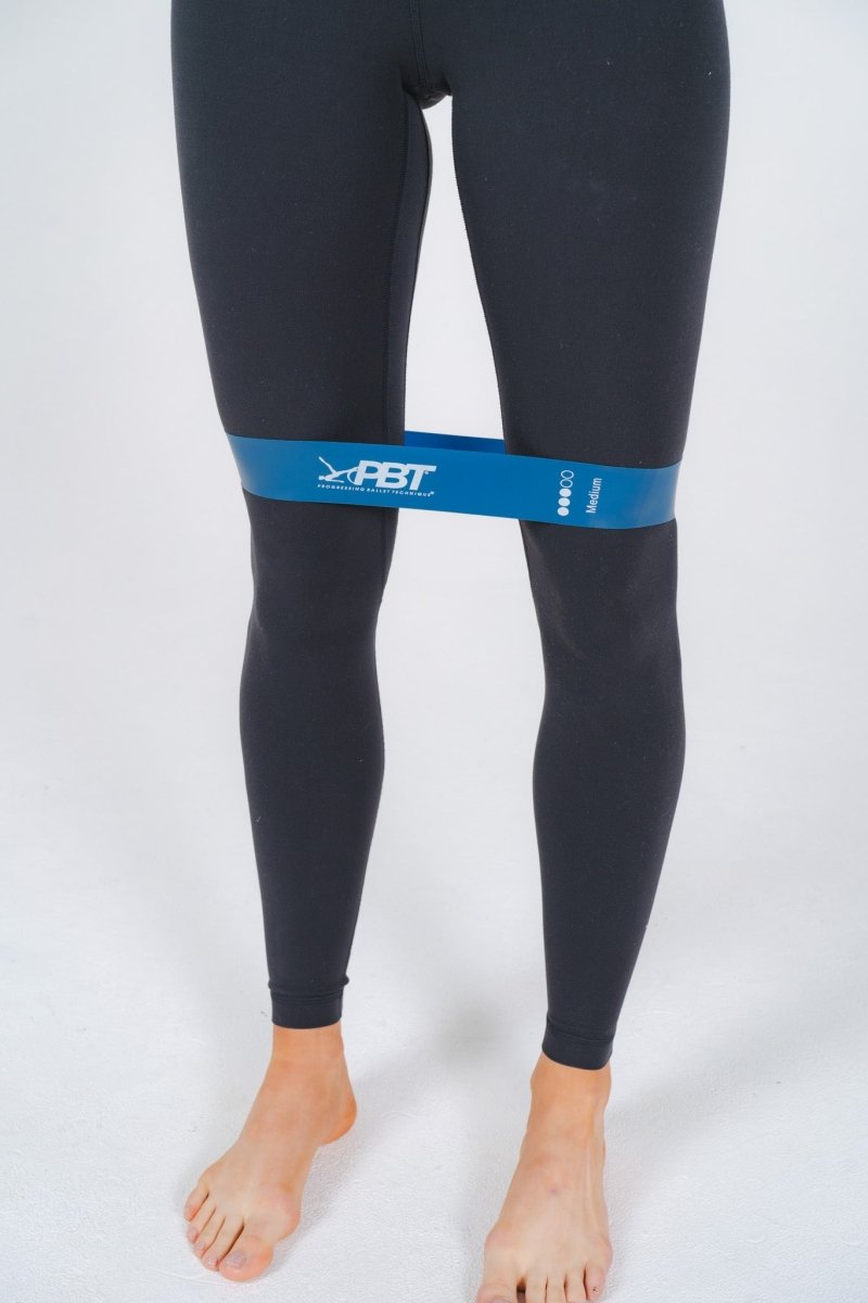 Blue PBT mini-loop band positioned at ankles for side step exercise