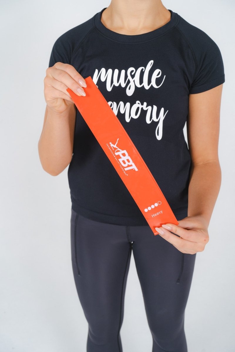 Person holding orange PBT mini-loop band from five-pack resistance set