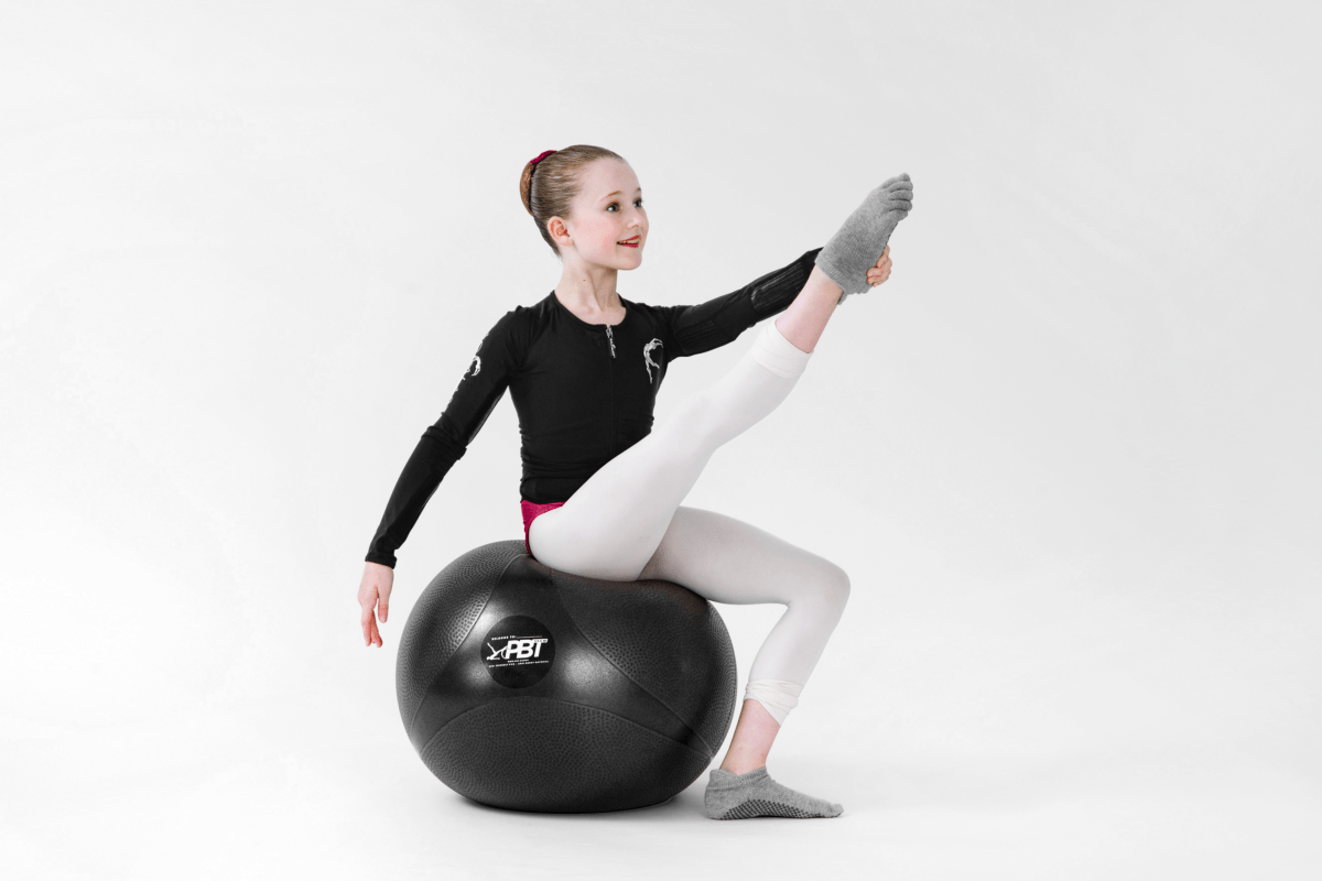 Ballet dancer performing controlled leg extension using PBT ball