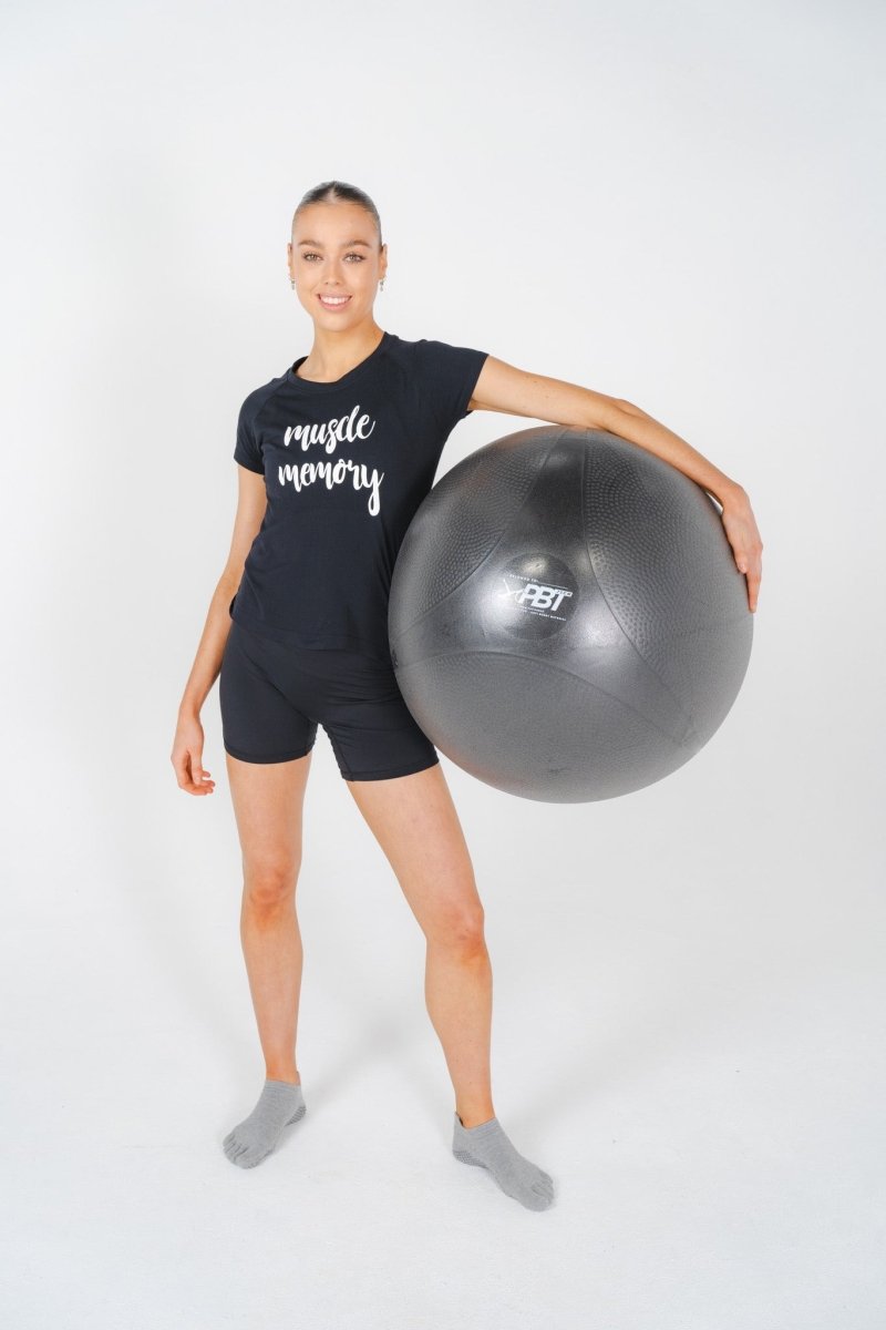 Ballet dancer standing and holding PBT ball for posture exercise