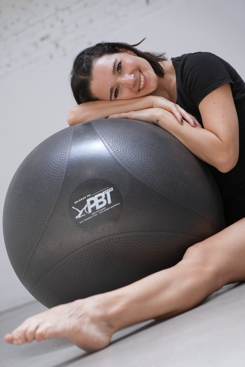 Dancer lying on floor with PBT ball for core stability training